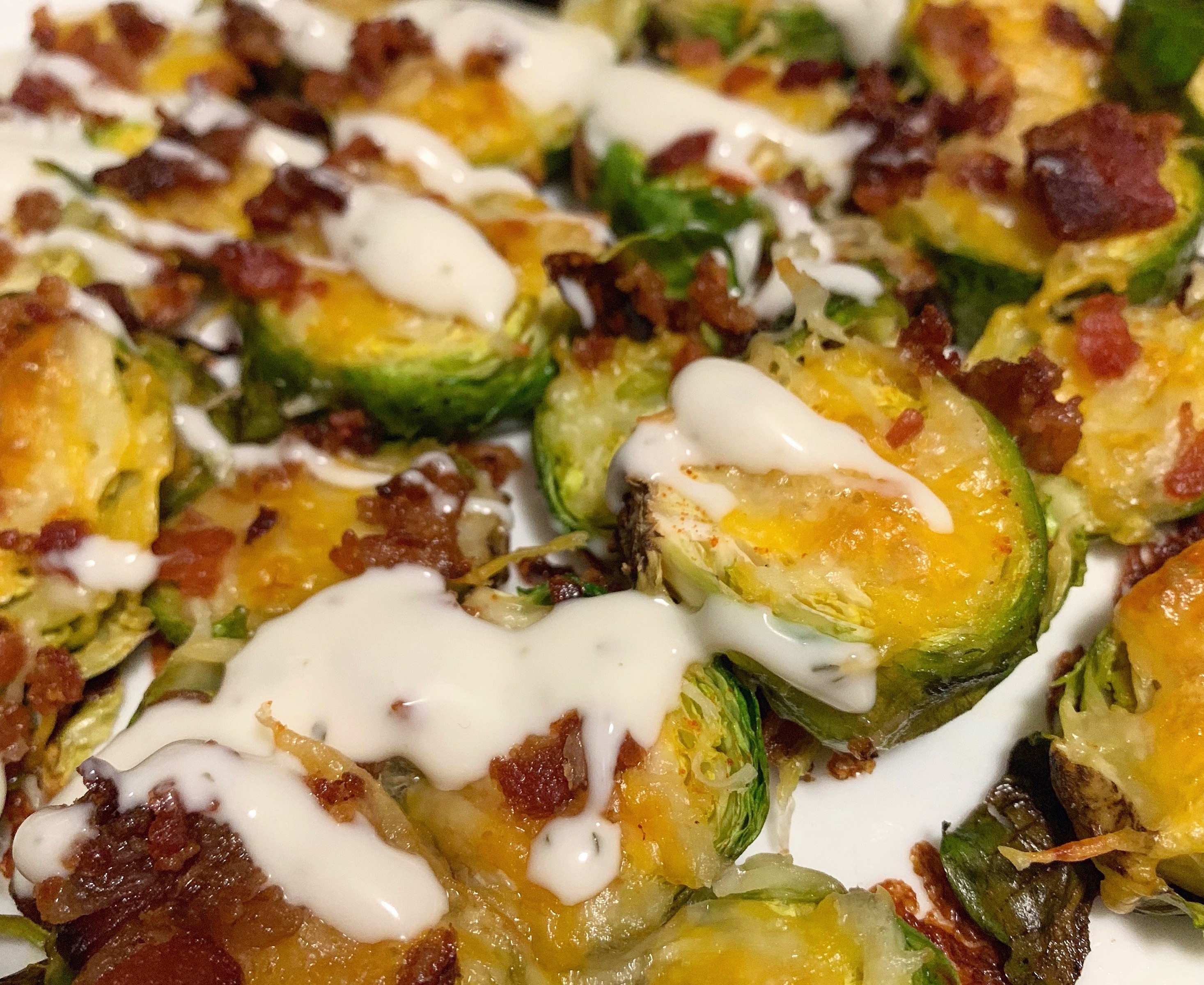 Roasted brussels sprouts with ranch, bacon bits and melted cheese