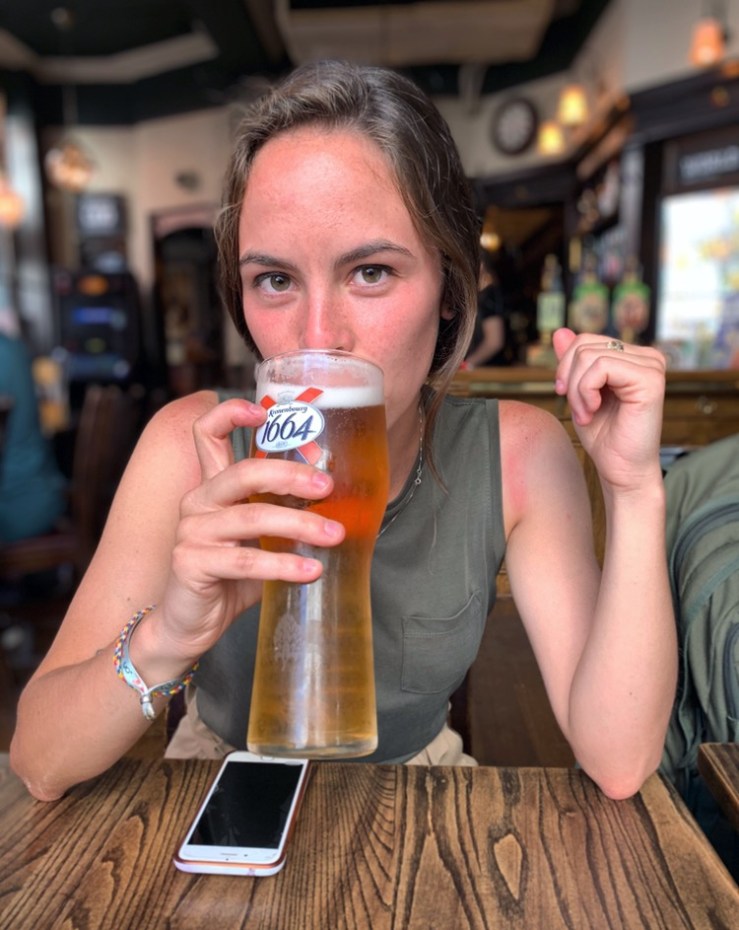 Marisa drinking a beer with her phone on the table