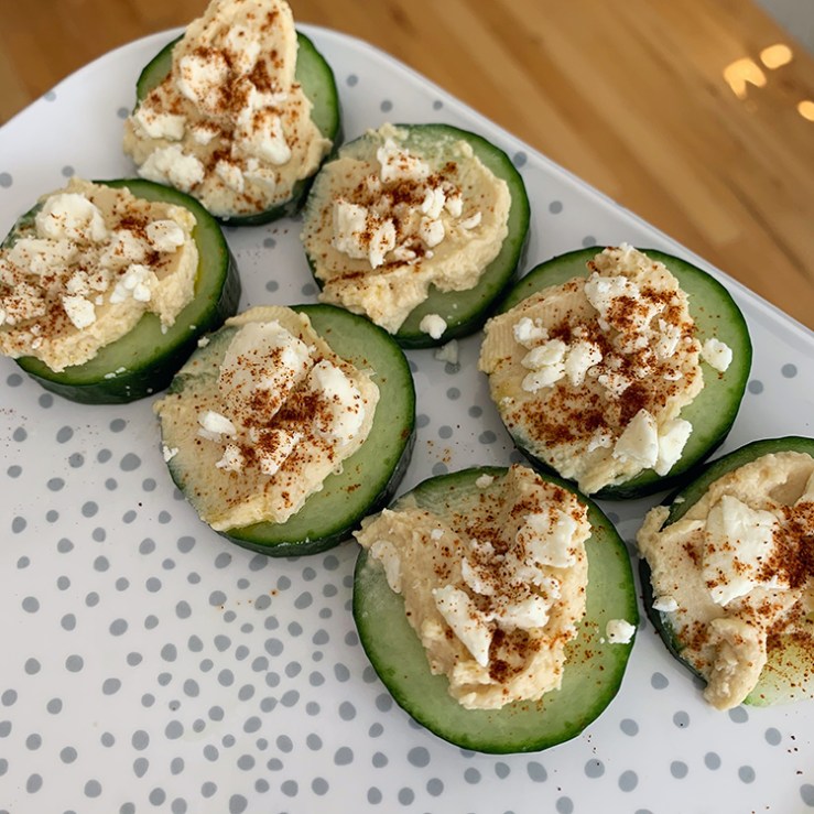 Cucumber slices with hummus and feta on a polka dot plate